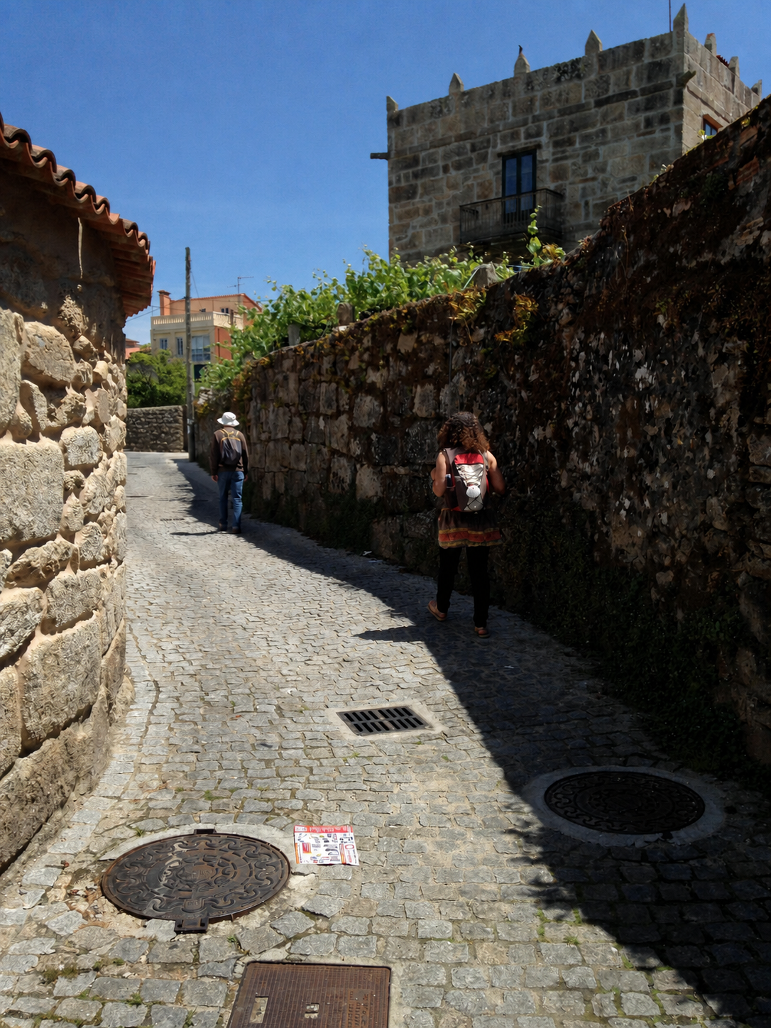 Two walkers following a historic stone lane on the Camino.