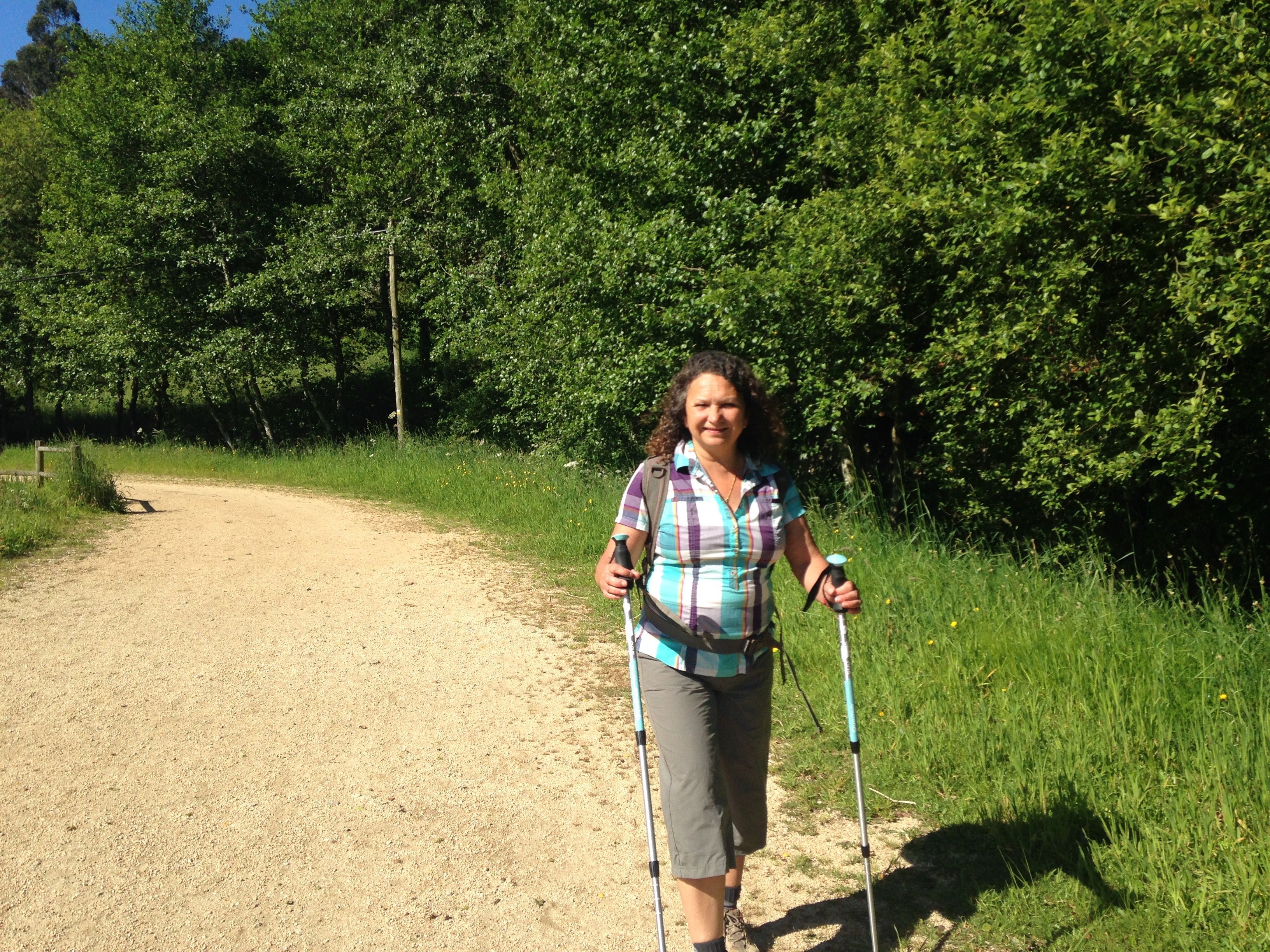 A pilgrim walking along a wooded Camino path in Galicia.